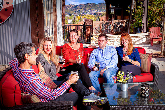 Five friends having drinks at outdoor cafe.