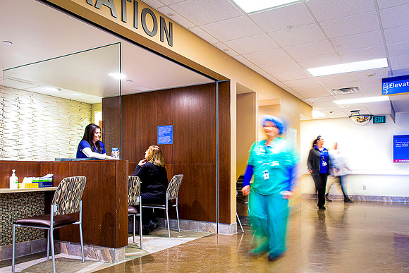 Nurses and other employees walk down a hallway in a hospital.
