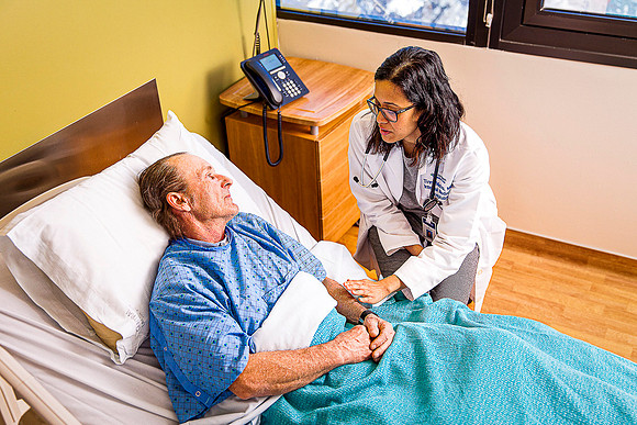 Woman doctor attends to male patient in hospital.