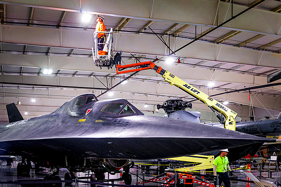 Electrician works above a Blackbird spy plane in an aerospace museum.