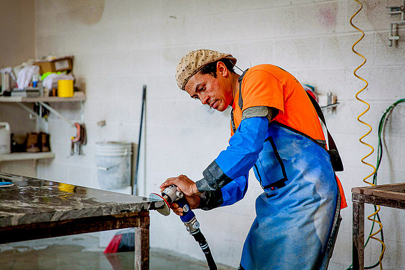 Artisan worker polishes the edge of a granite countertop.