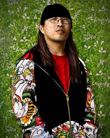 Interesting Asian man in colorful jacket poses at art exhibit..