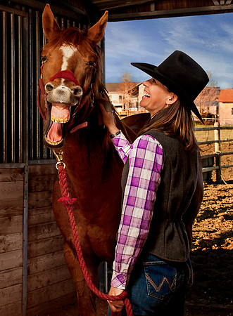 Woman rancher in a stable with whinnying horse.