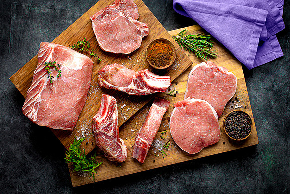 An assortment of different pork meat cuts on cutting board.