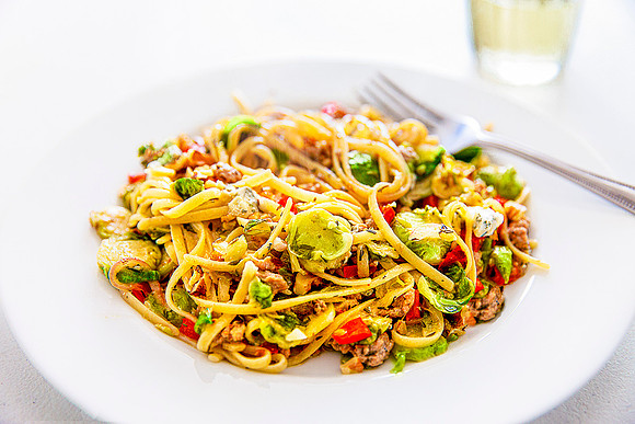 A plate of linguine with brussels sprouts, red pepper and walnuts.
