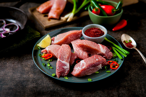 Raw pork pieces to become carnitas on a plate.