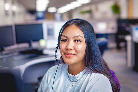 Young woman at desk in office with headset.