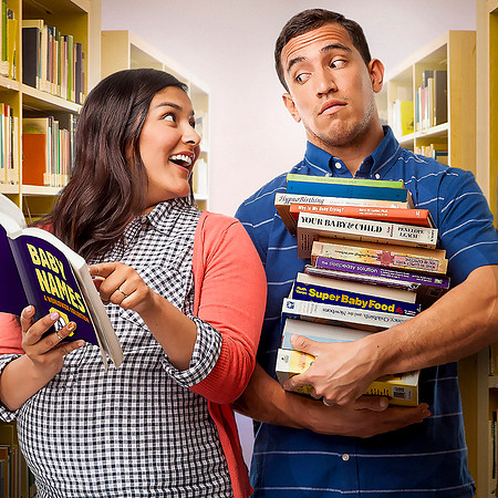 Expectant couple in bookstore with many baby care books.