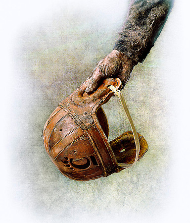Vintage leather football helmet held by player.