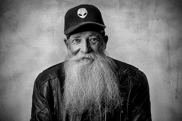 Portrait of an eccentric older biker man with a huge beard and black leather jacket.