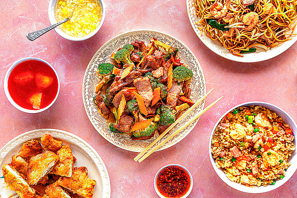 Several Chinese restaurant food dishes on  pink table.