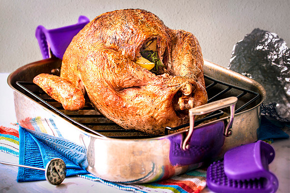 A whole roasted turkey, just removed from the oven in its roasting pan.