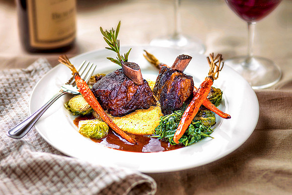 Bison short ribs and vegetables on white plate.