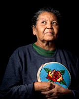 Ute tribe older woman looks afar holding handmade purse.