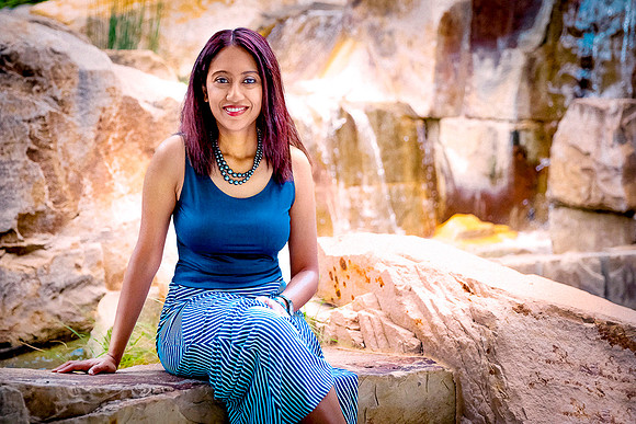 Attractive lady doctor sits by waterfall in dress.